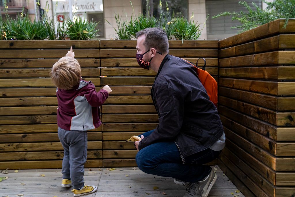 Un niño pequeño mostrándole a su padre unas plantas de las jardineras que delimitan la acera ampliada de los alrededores de la Escuela Marillac