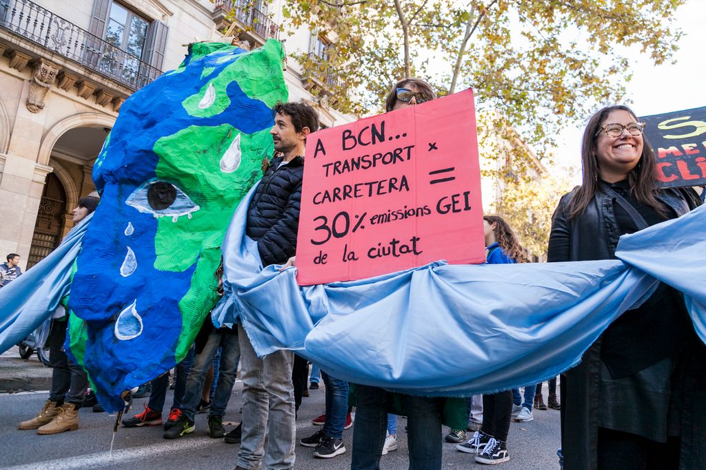 Grup de manifestants amb una gran màscara d'una cara pintada amb un fragment dels continents i oceans per denunciar les emissions de gassos d'efecte hivernacle