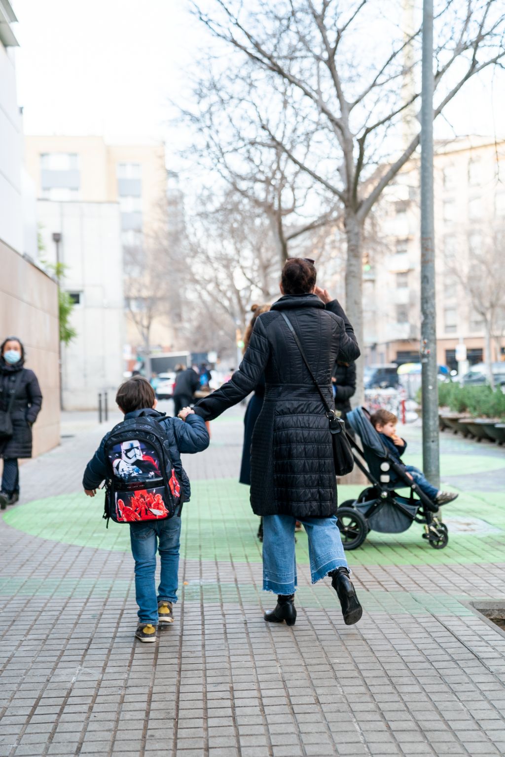 Una família s’allunya de l’escola caminant per la vorera de la zona pacificada al voltant de l’Escola Grèvol