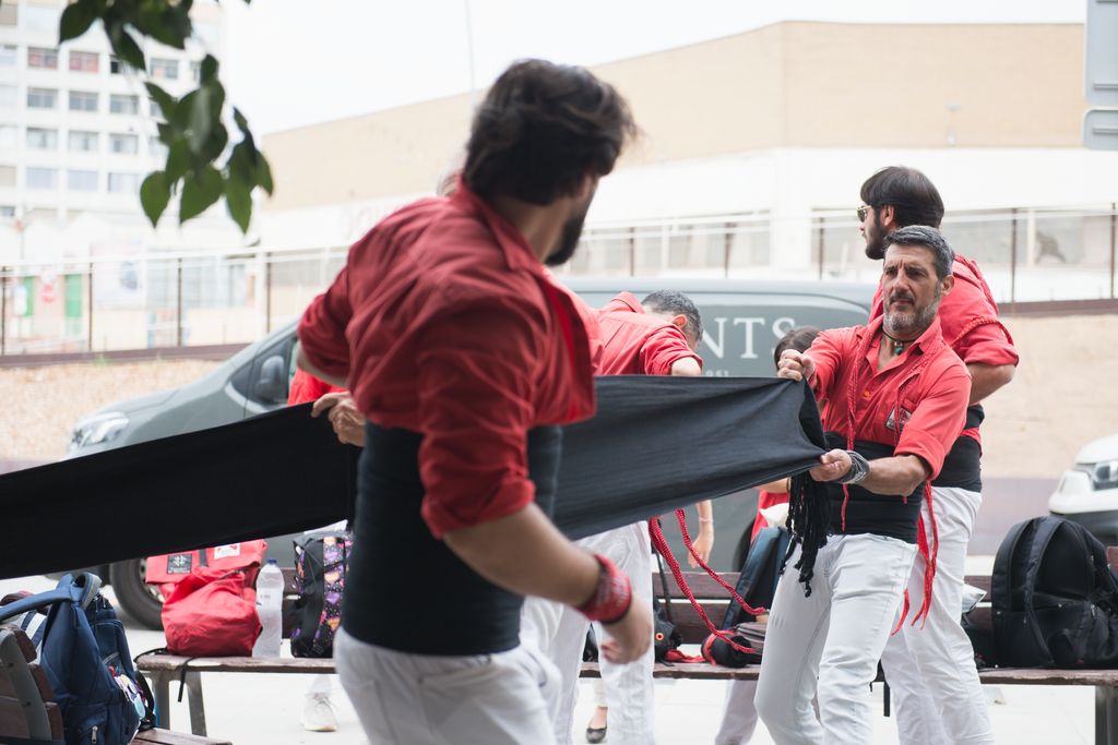 Un ‘casteller’ ayuda a un compañero a ponerse la faja antes de la actuación durante la fiesta popular inaugural del puente de Santander