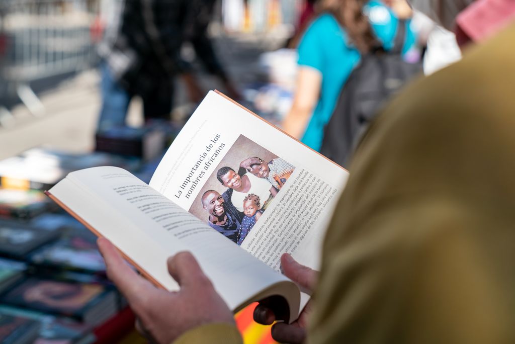 Una persona hojeando un libro en un puesto montado en la plaza Reial con motivo del Día de Sant Jordi