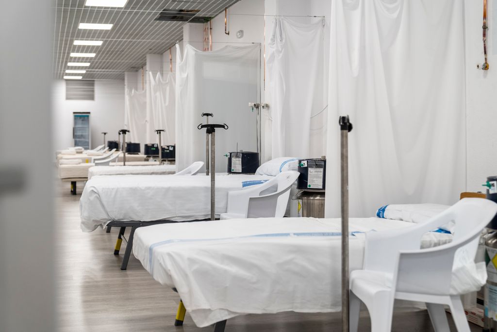 Sala del Pavelló Salut Vall d’Hebron amb llits, bases per a bosses de sèrum i medicació i separadors de cortina