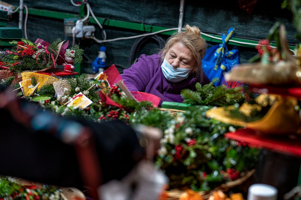 La venedora d’una parada de vesc i altres decoracions vegetals atén una clienta a la Fira de Nadal a Sagrada Família
