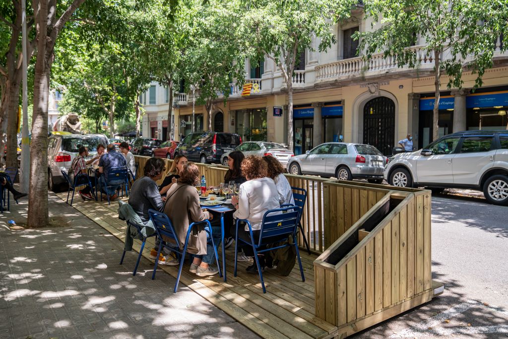 Clients asseguts a les taules exteriors d’un restaurant que té instal·lat un dels nous prototips de terrasses fetes amb fusta i amb les jardineres encara sense plantes