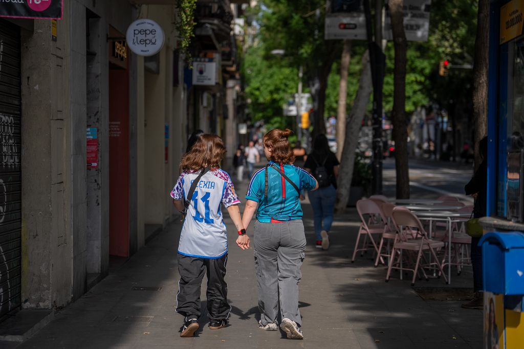 Dos chicas con camisetas del FCB caminan cogidas de la mano.