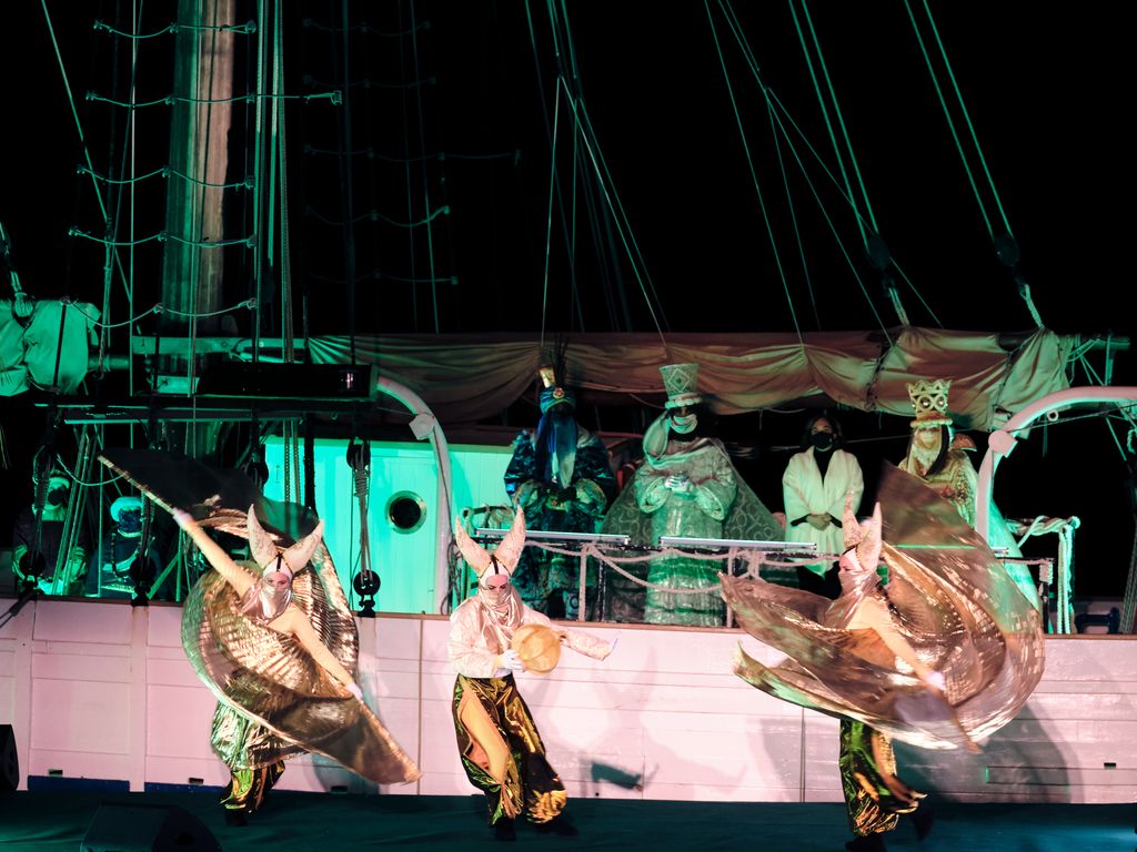 Membres del seguici dels Reis d'Orient ballant a l'escenari davant del pailebot 'Santa Eulàlia', des d'on se'ls miren els tres Reis i l'alcaldessa, Ada Colau