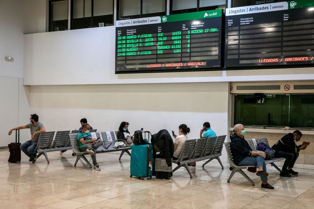 Vestíbul de l'estació de Sants amb viatgers esperant asseguts als bancs i conservant les distàncies tal com indiquen els cartells informatius als seients