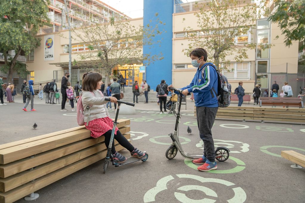 Una nena seu mentre conversa amb un altre infant a un dels bancs de la zona pacificada davant de l'Escola Lavínia en el marc del programa Protegim les escoles