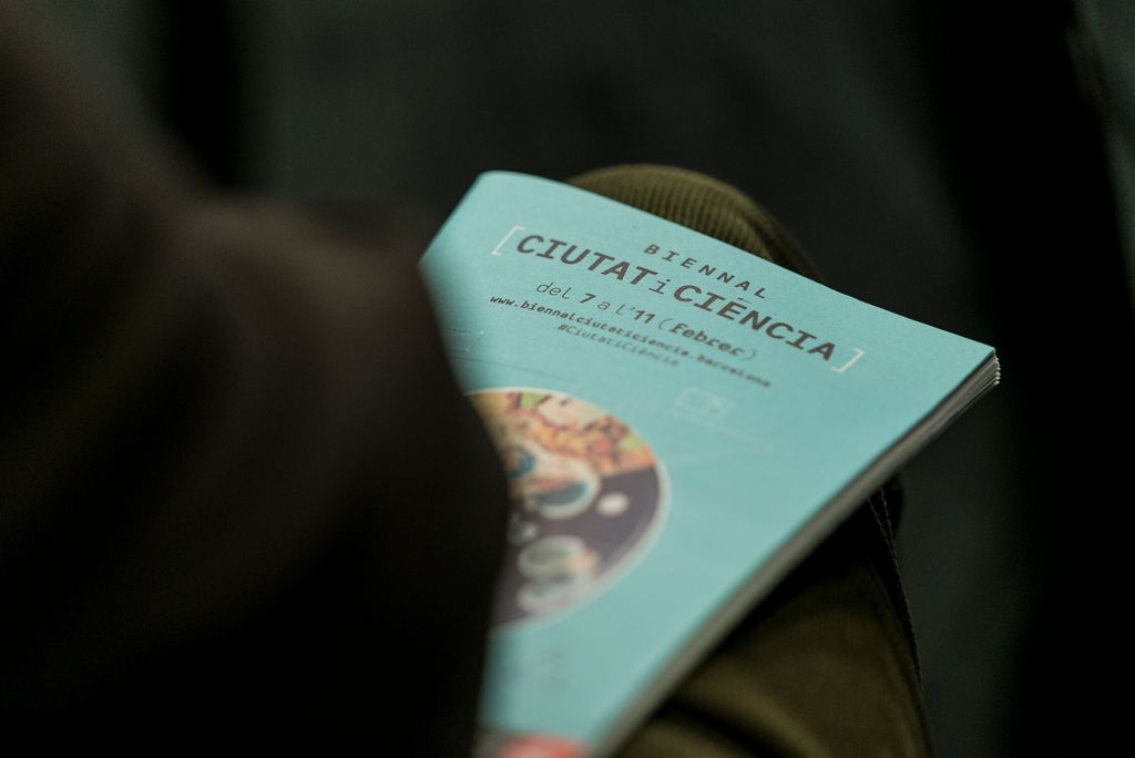 Un dels assistents amb el programa de la Biennal Ciutat i Ciència a la falda