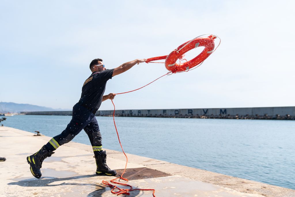 Un bomber pràctica el llançament d’un salvavides amb balisa a l’aigua del Port del Fòrum