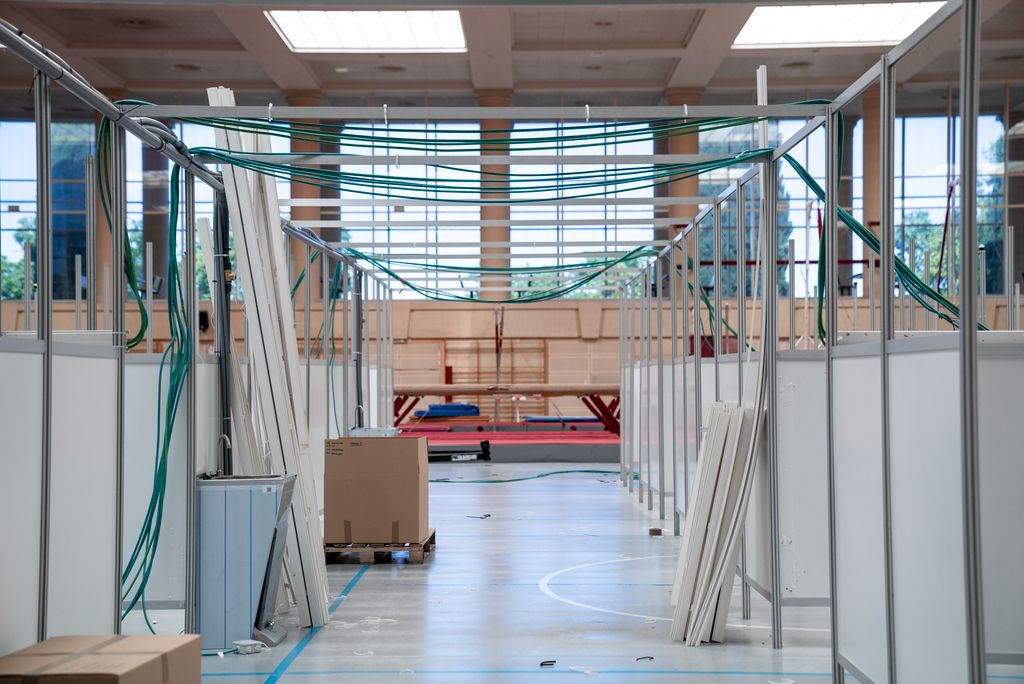 Emplafonat d'una de les sales Pavelló Salut de l'INEFC a mig desmuntar amb el cablejat a la vista, carretons amb material, fonts d'aigua i, al fons, unes barres d'equilibri