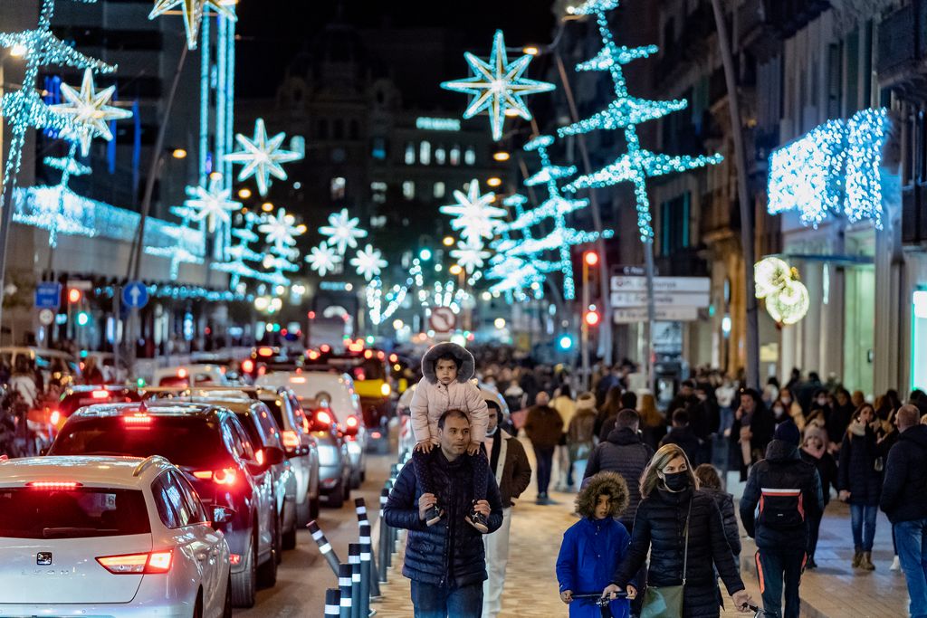 Calle Pelai con gente paseando por la acera táctica y de obra y vehículos circulando bajo las luces de Navidad