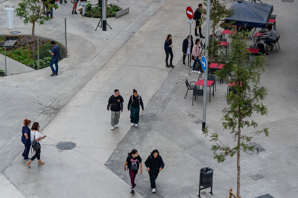 Gente caminando por el nuevo eje verde de las calles de los Almogàvers y Zamora mientras otros están sentados en una terraza