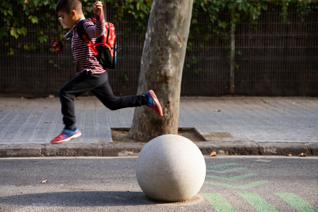 Un nen salta d'una esfera de ciment  davant de l'Escola Antoni Brusi, un dels entorns pacificats al programa 'Protegim les Escoles'