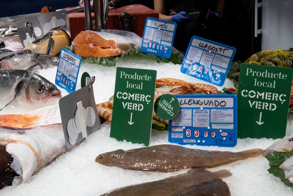 Parada de peix del Mercat de Sarrià amb uns peixos frescos, i en alguns d’ells el rètol al costat d’un llenguado que l’identifica com a “Comerç verd, producte local”