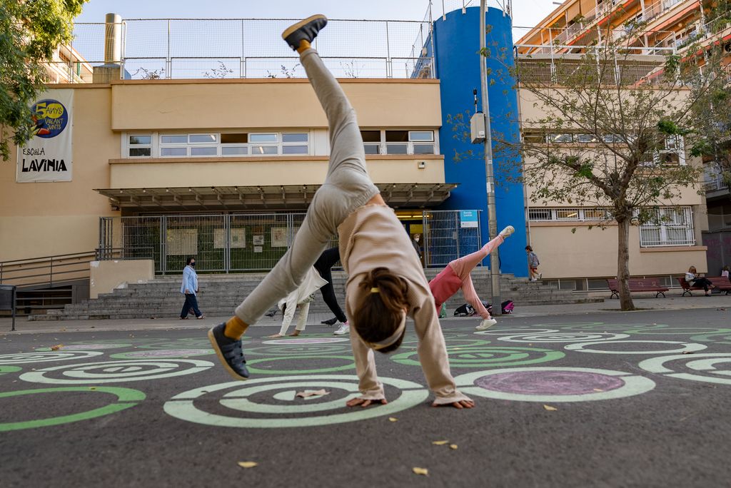 Una nena juga fent tombarelles a la zona pacificada del carrer davant de l'Escola Lavínia