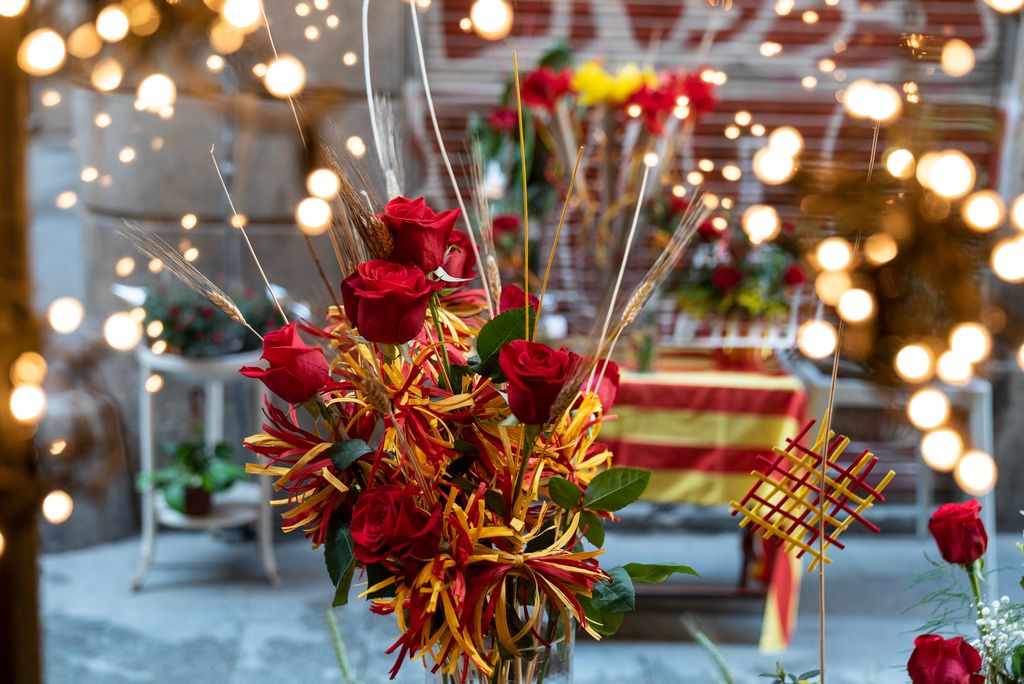 Rosas con espigas y decoración en amarillo y rojo en el escaparate de una floristería con motivo del Día de Sant Jordi