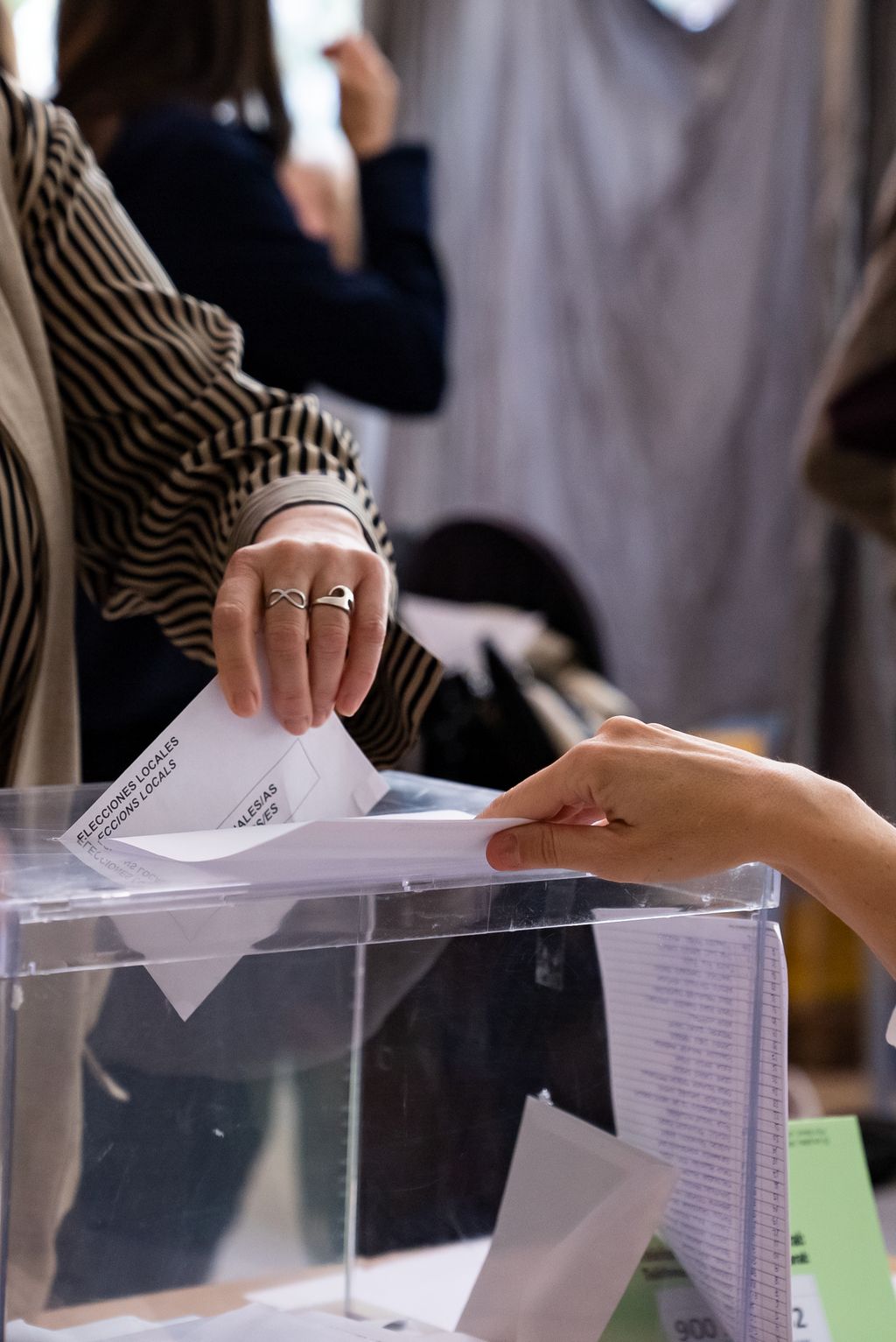 Detall d’una mà introduint un sobre a una urna durant la jornada d’eleccions municipals 2023.