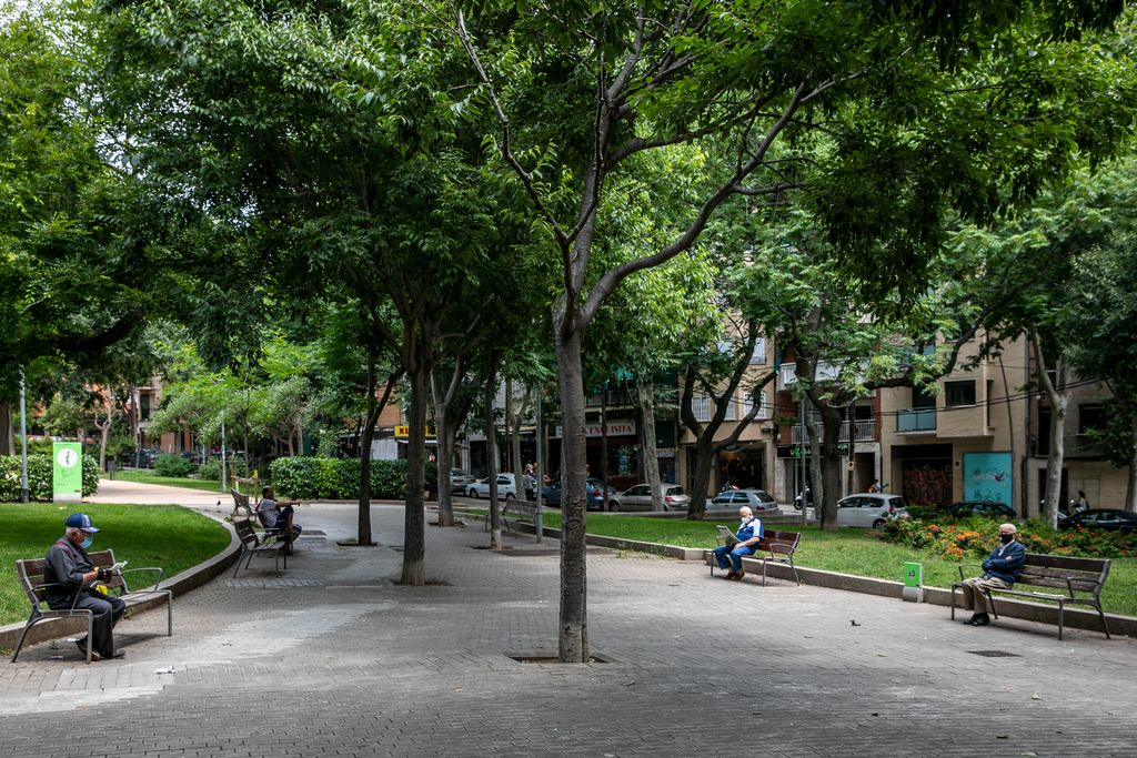 Jardins de Llucmajor amb uns homes grans asseguts cadascú en un banc i una parella en un altre a fi de mantenir la distància de seguretat
