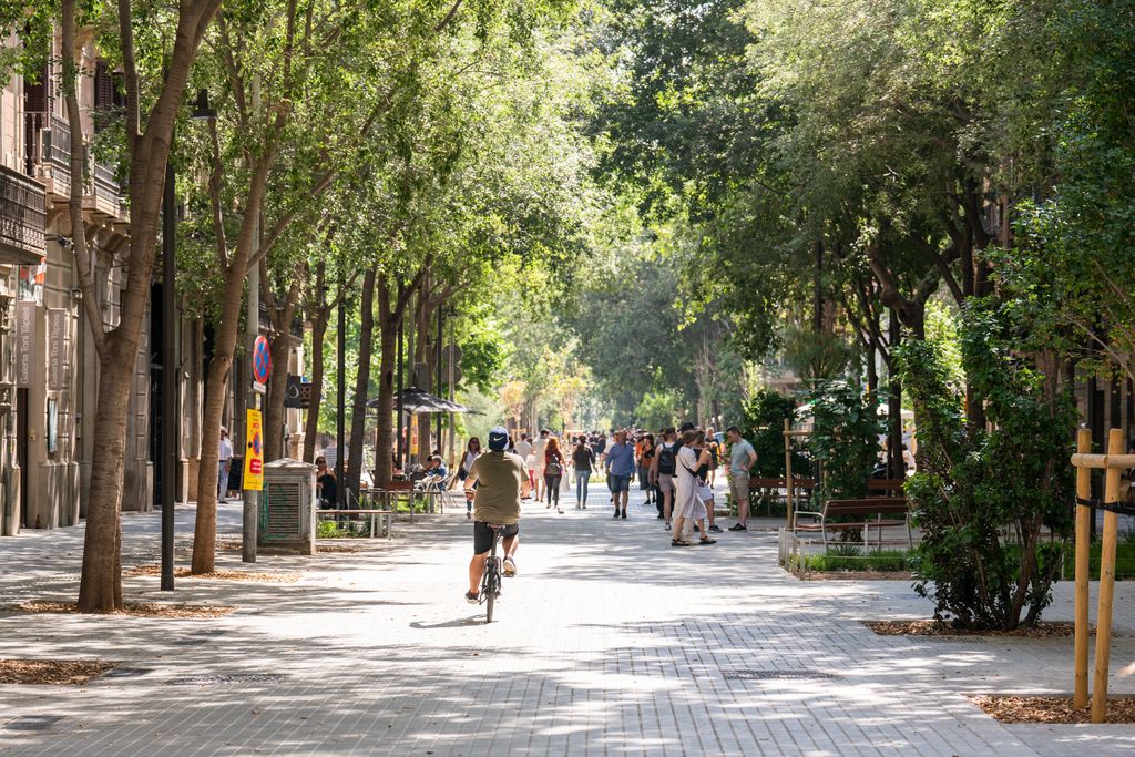 Un noi en bicicleta al centre del carrer de l’eix verd de Consell de Cent. Al fons, gent passejant.