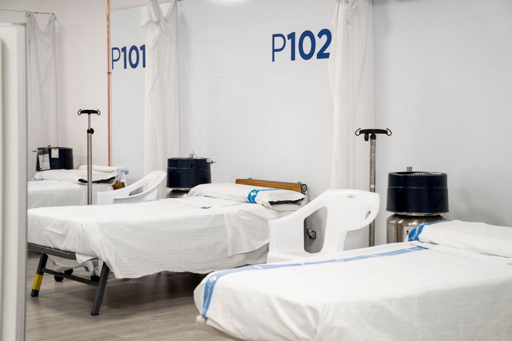 Sala del Pavelló Salut Vall d’Hebron amb llits, bases per a bosses de sèrum i medicació i separadors de cortina