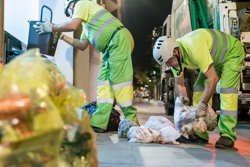 Escombraires recollint les bosses de brossa dels portals per posar-los al camió a Sarrià