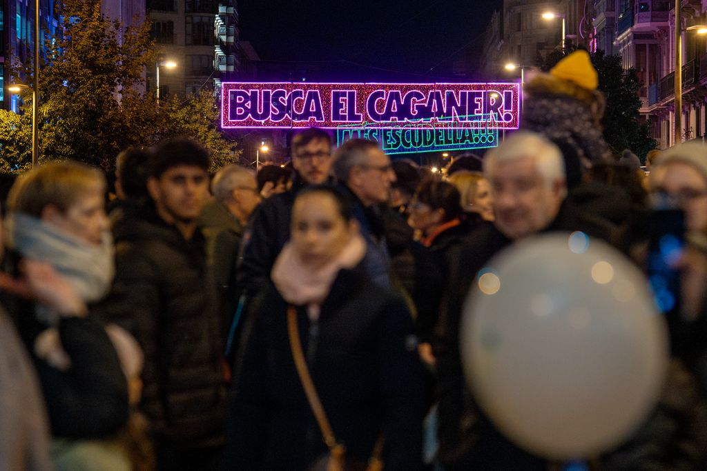 Gent passejant i mirant els llums de Nadal amb frases que es diuen per Nadal, al carrer d’Aragó el dia de l'encesa de llums