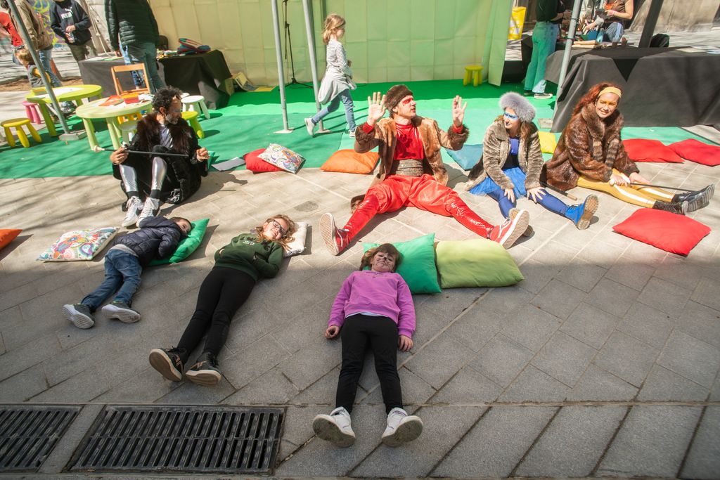 Uns nens s’estiren al costat d'Els il·luminats, de Sergi Estebanell, en una carpa situada al carrer del Consell de Cent, entre el carrer d'Enric Granados i la rambla de Catalunya durant la festa d'inauguració de la Superilla de Barcelona.