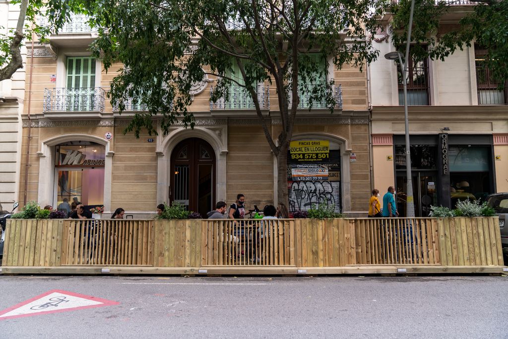 Clients asseguts a les taules exteriors d’un restaurant que té instal·lat un dels nous prototips de terrasses fetes amb fusta que contenen jardineres amb plantes