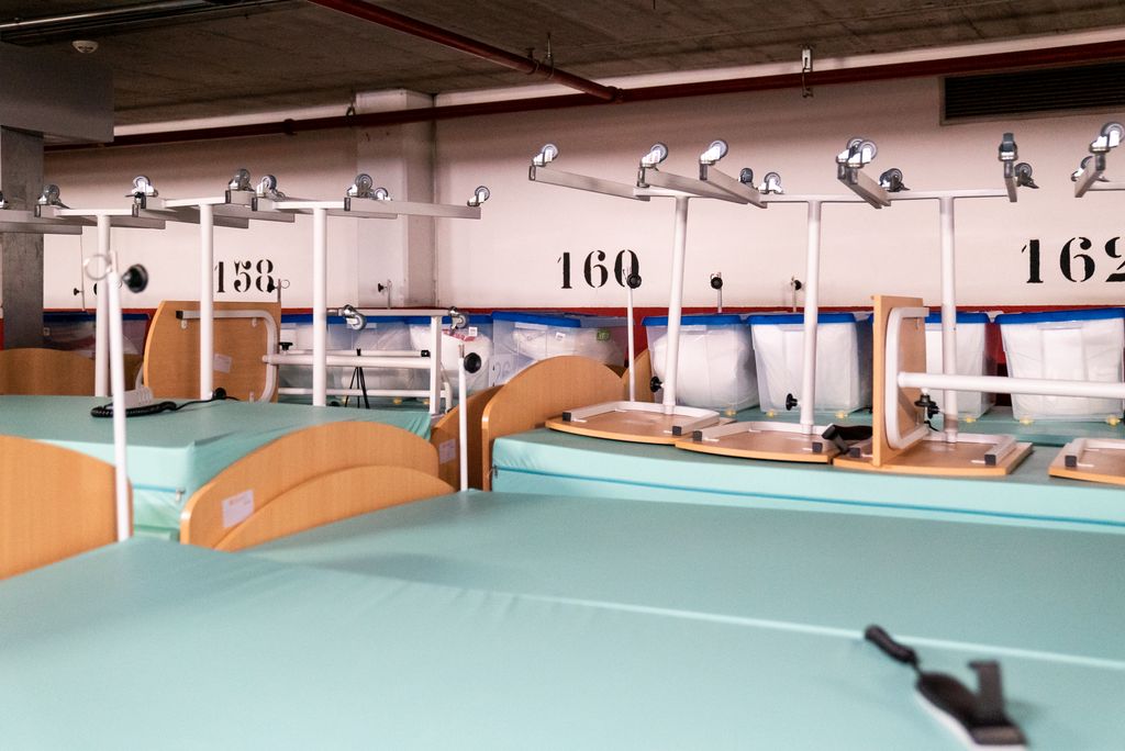 Llits amb matalassos i taules emmagatzemats a l'aparcament buit del CEM Claror (Pavelló Salut) a l'espera de ser recollits