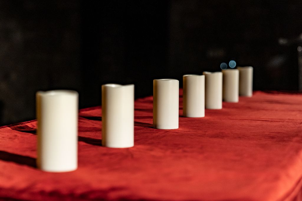 Sobre una taula, set espelmes apagades perquè les encenguin els representants dels diferents col·lectius de víctimes de l'Holocaust durant l'acte commemoratiu al Saló del Tinell