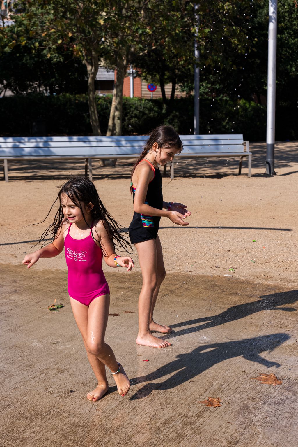Dues nenes en banyador jugant a la zona d'aigua del parc de les Rieres d'Horta