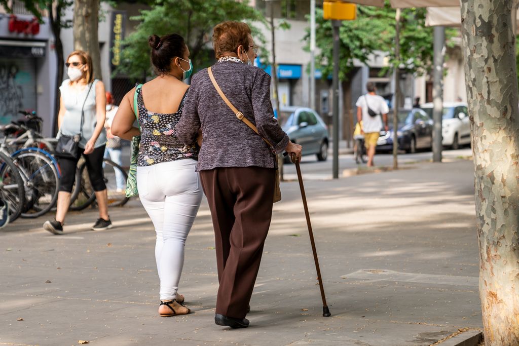 Una dona jove acompanya durant el passeig una dona gran amb bastó pel passeig de Fabra i Puig, que està tancat a la circulació de vehicles