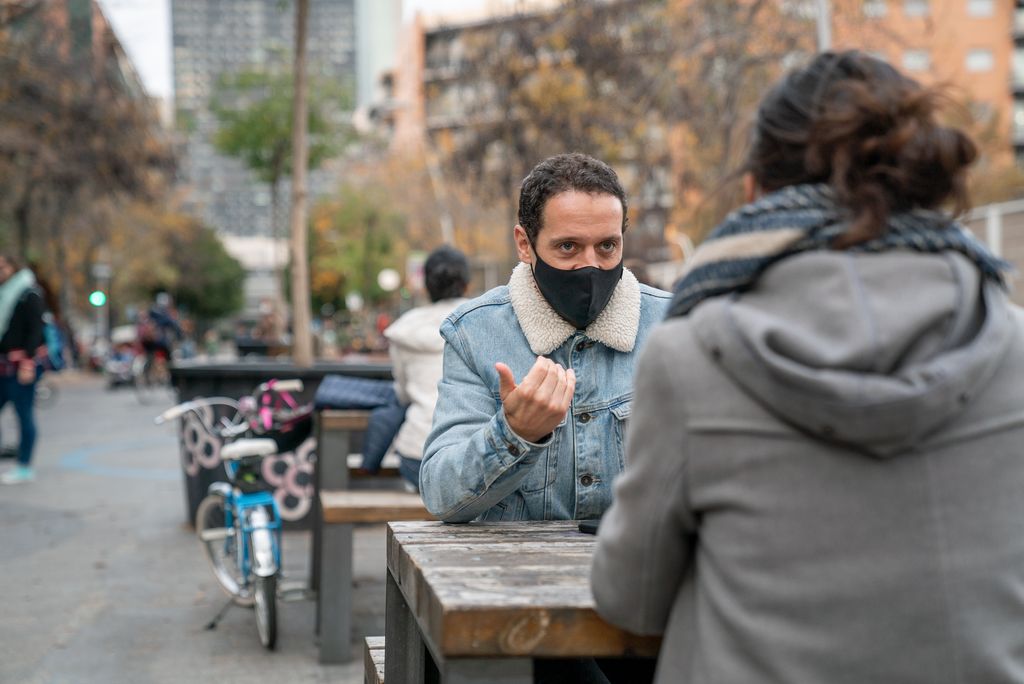 Dues persones conversen en una de les taules de pícnic de la superilla del Poblenou