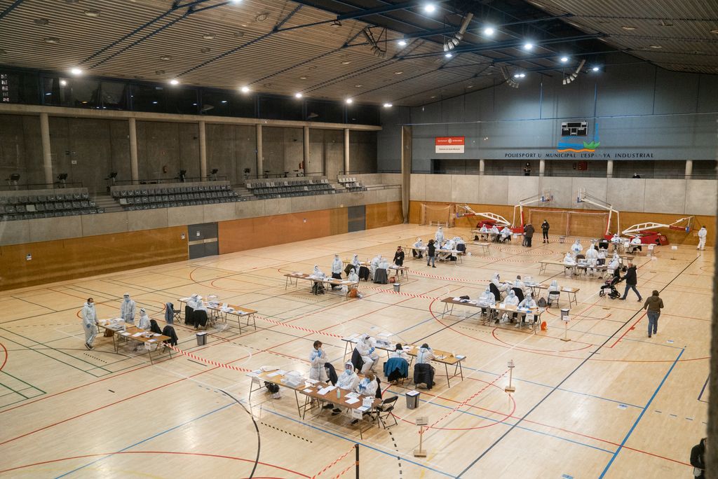 Interior del Centre Esportiu Municipal l'Espanya Industrial, a la pista, durant la última hora de la jornada electoral del 14-F, es veuen repartides les diferents meses amb els membres vestits amb els equips de protecció individual