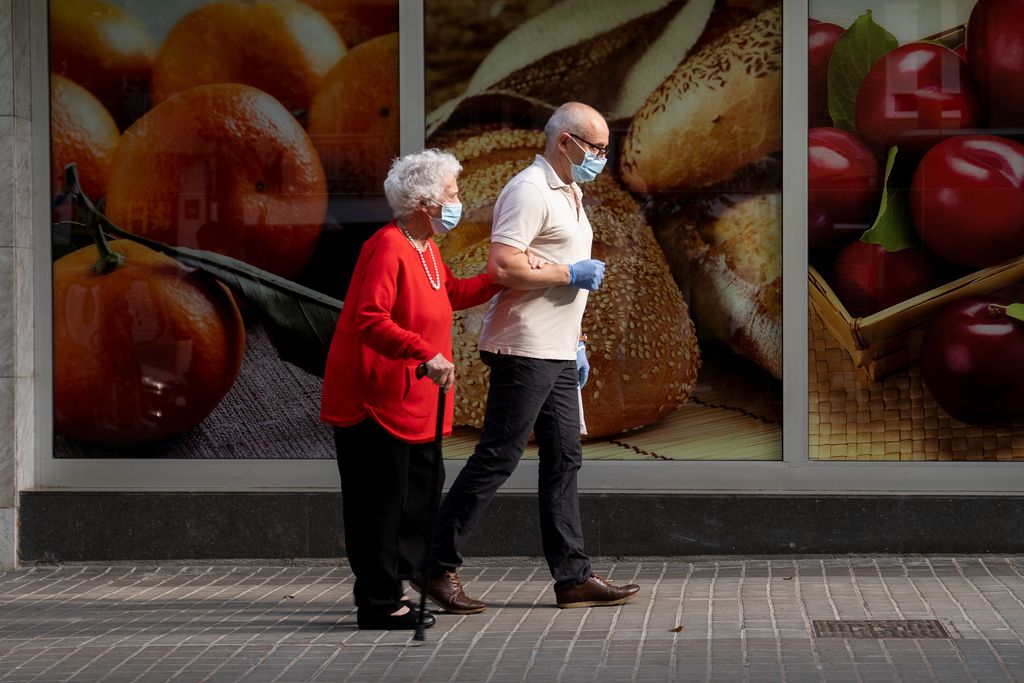 Un home acompanya durant el passeig una dona gran que camina amb bastó pel passeig de Fabra i Puig