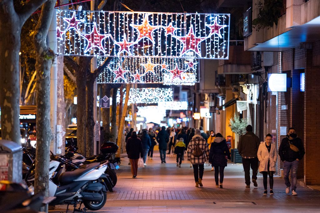 Gente caminando y realizando compras por el paseo de Fabra i Puig bajo las luces de Navidad del eje comercial