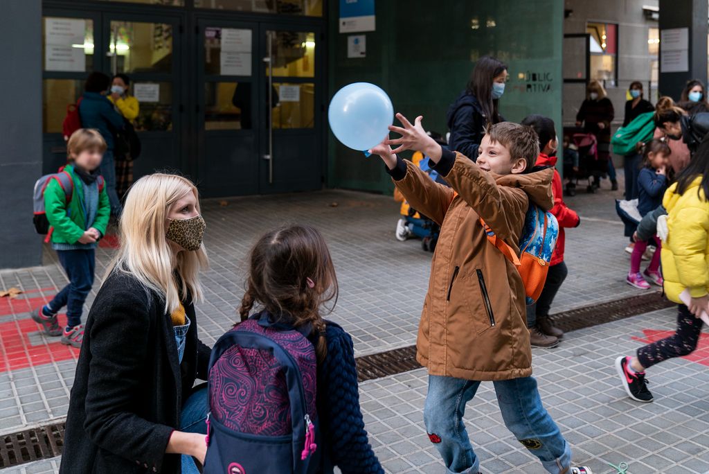 Uns nens juguen amb un globus a la zona pacificada de vorera ampliada de davant de l’Escola Carlit