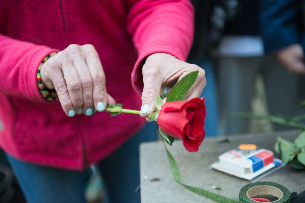 Detall de les mans d’una florista de la Rambla arranjant una rosa.