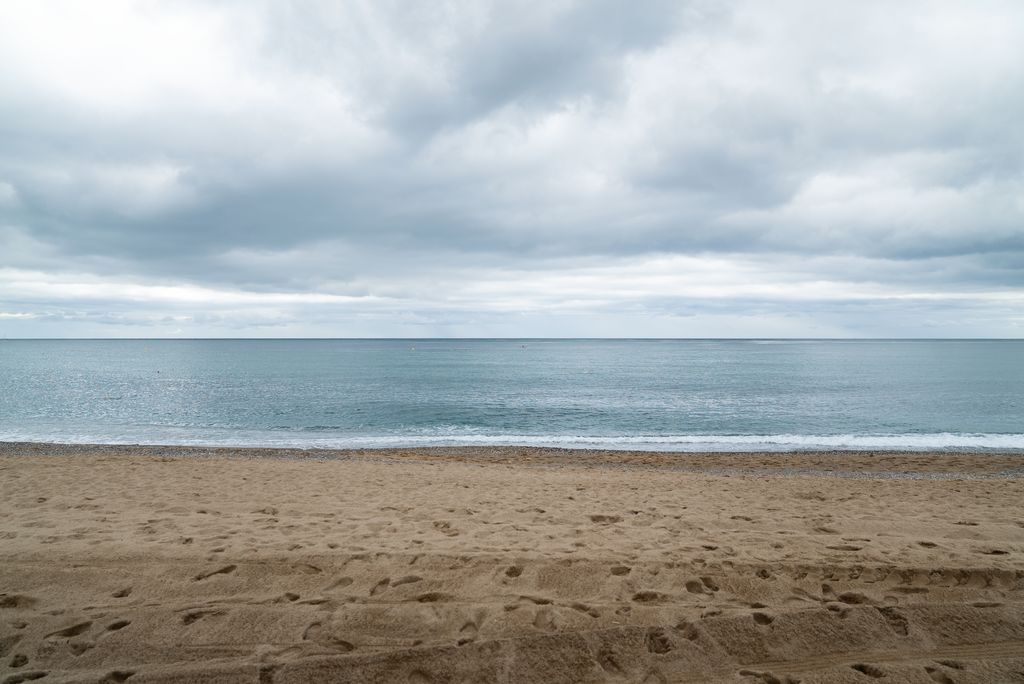 Platja de Sant Miquel durant un dia ennuvolat sense ningú a la sorra i el mar en calma