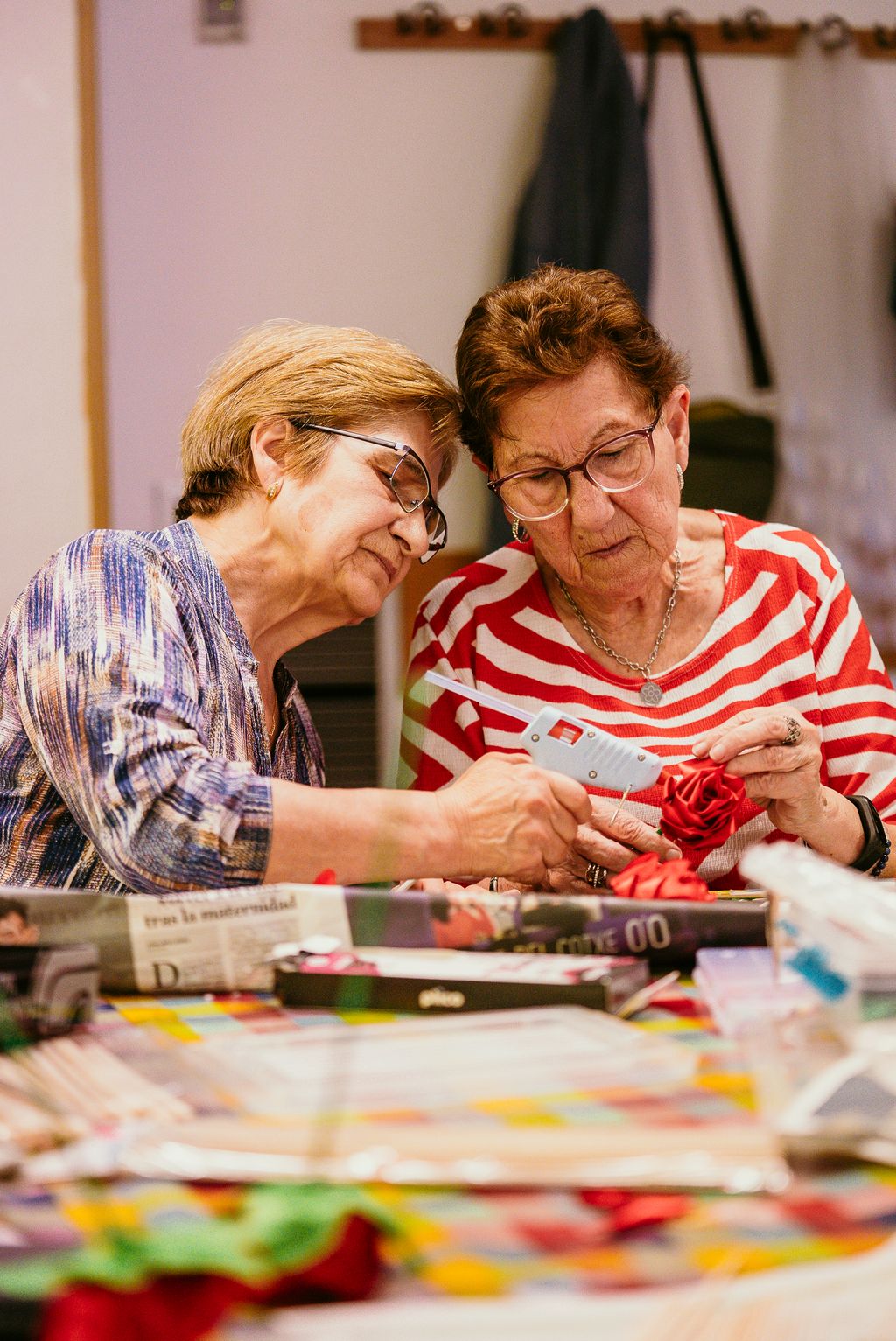 Dos mujeres trabajan juntas creando una rosa en el taller “Rosas de Sant Jordi” en el Casal de Gent Gran Turó de la Peira.