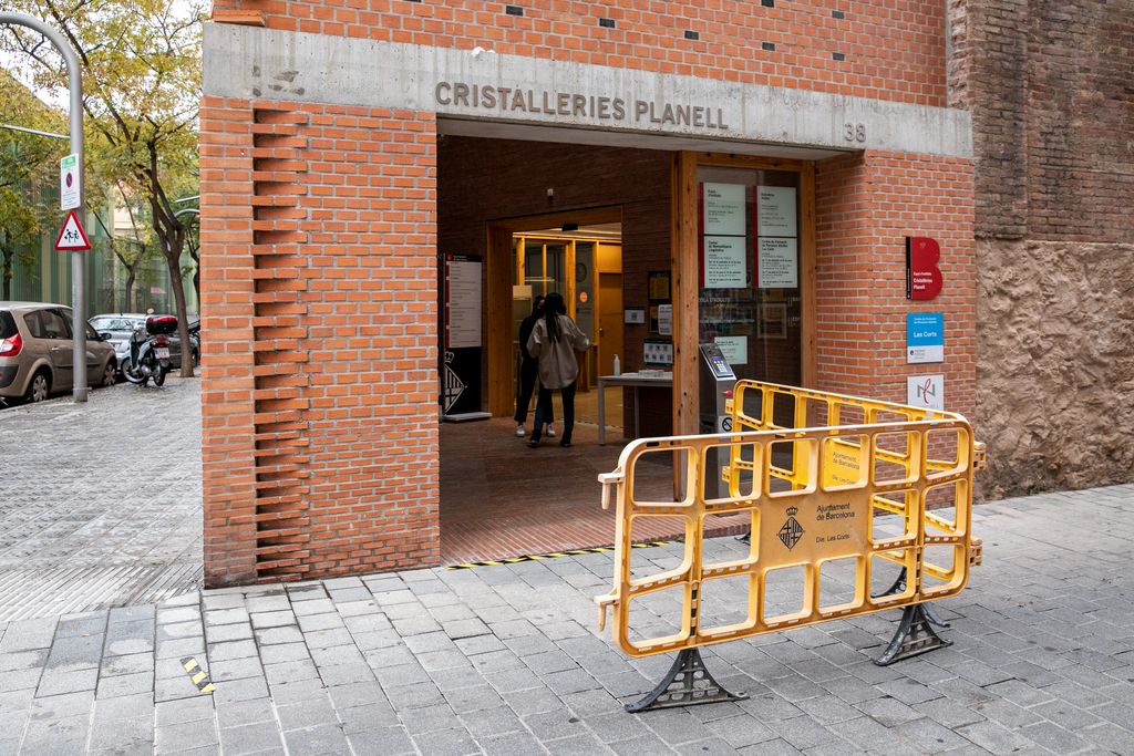 Exterior de les Cristalleries Planell, on hi ha un dels col·legis electorals de Les Corts, amb gent que s'espera a l'interior
