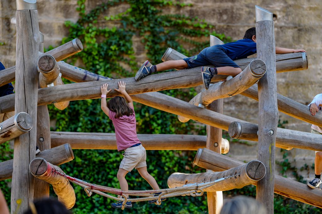 Niños y niñas trepando por un juego infantil con troncos y redes en el parque del Aqüeducte durante las fiestas de La Mercè