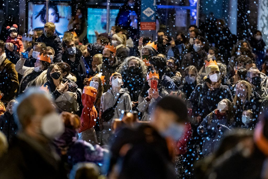 Familias con niños siguiendo el paso de la Cabalgata de Reyes mientras cae nieve artificial