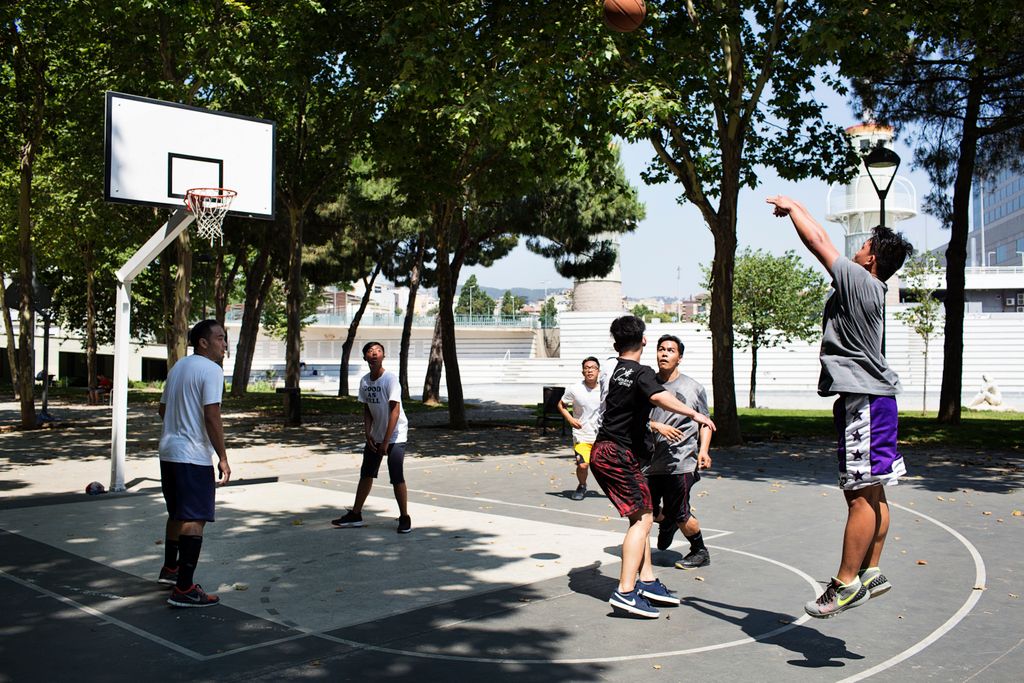 Homes jugant a la pista de bàsquet al Parc de l'Espanya Industrial