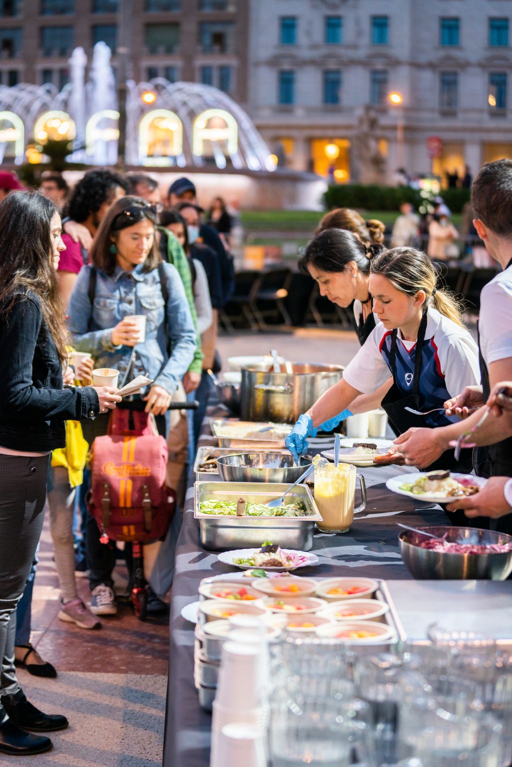 Miembros de la Plataforma Aprovechemos los Alimentos sirven los platos a los comensales de la cena de la plaza de Catalunya