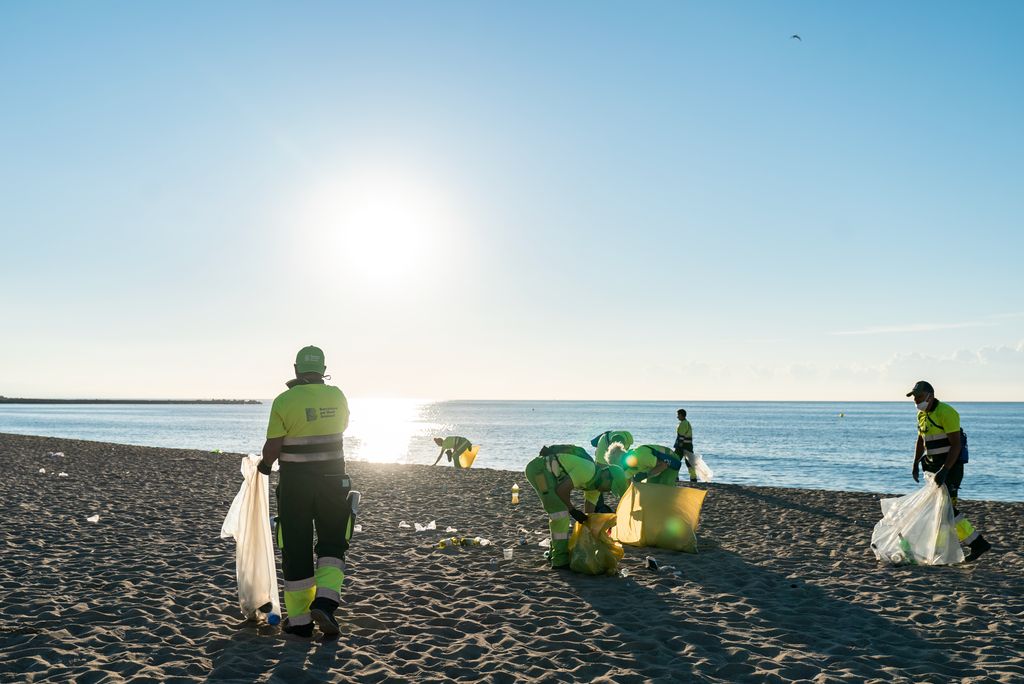 Personal del servei de neteja de Barcelona pel medi ambient recollint de manera selectiva els residus que la gent ha deixat a la sorra de la platja del Bogatell durant la celebració de Sant Joan