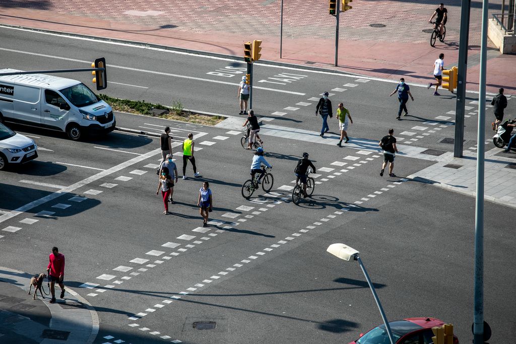 Persones i bicicletes travessant el pas de vianants de l'avinguda del Paral·lel amb la plaça d'Espanya
