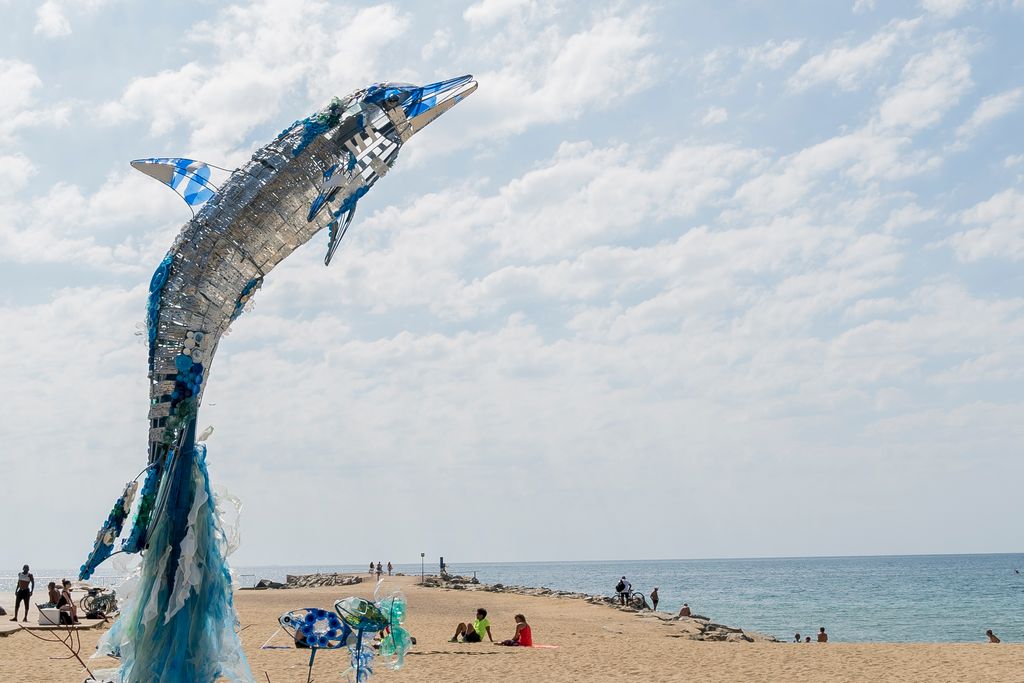 Instal·lació escultòrica a la platja d'un dofí i el seu entorn marí fet amb materials reciclats