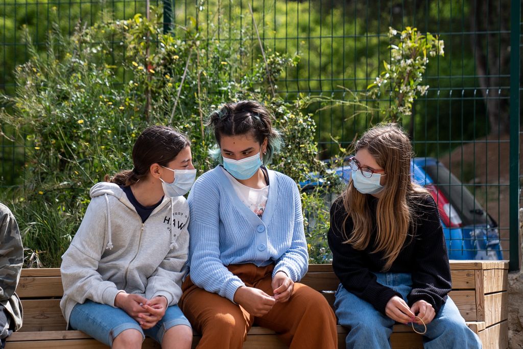 Uns adolescents conversen asseguts al pati de l’escola
